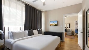 Habitació d'hotel moderna amb un llit gran, un escriptori i vista a la ciutat a través de la finestra.