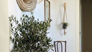 A room with a woven basket table, a wooden chair, a hanging woven hat, and a potted plant. - Maison vue Mer , Proche Bastia (Bastia)