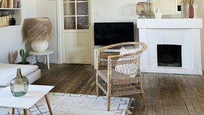 A cozy living room with a fireplace, a television, and a wicker chair. - Maison vue Mer , Proche Bastia (Bastia)