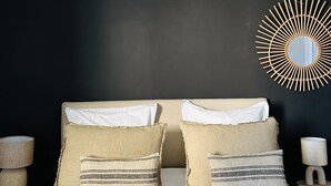 A bed with two pillows, a woven headboard, and a wall-mounted mirror. - Maison vue Mer , Proche Bastia (Bastia)