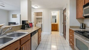 Een moderne keuken met roestvrijstalen apparatuur, houten keukenkastjes en een betegelde achterwand.