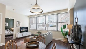 Ein modernes Wohnzimmer mit Essbereich, großen Fenstern und Blick auf die Stadt.