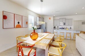 A modern dining area with a wooden table, orange chairs, and a vase of flowers.