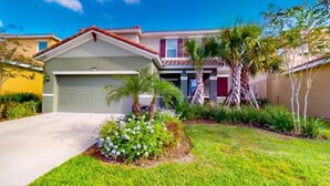 A residential house with a garage, a well-maintained lawn, and palm trees. - Beautiful 5 Bed Pool Home with Game Room (Davenport)