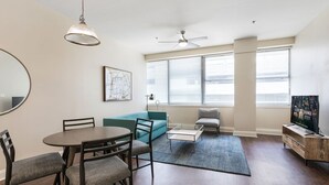 A modern living room with a dining table, sofa, and TV stand.