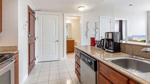 A modern kitchen with a stainless steel sink, a coffee maker, and a dishwasher.