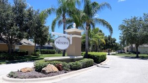 A sign for "The Preserve" with a clear road and palm trees in the background. - Spacious Family Pool Home with Game Room (Davenport)