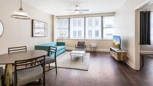 A modern living room with a dining table, sofa, and TV stand. - NOLA Escape: City Chic 1BR Condo with Rooftop Pool (New Orleans)