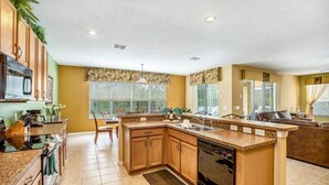 A spacious kitchen with granite countertops, wooden cabinets, and a built-in dishwasher. - Spacious and Relaxing Home with South Facing Pool (Davenport)