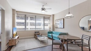 Una sala moderna con sofá, mesa de centro, televisor y mesa de comedor.