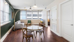 A living room with a round glass table, two wooden chairs, a sofa, and a floor lamp.