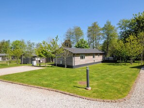 A row of single-story cabins with a gravel driveway and a grassy lawn.