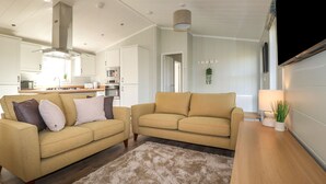 A modern living room with two sofas, a coffee table, and a TV. - 23 Meadow Retreat (Liskeard)