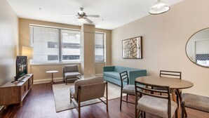 Ein stilvolles Wohnzimmer mit einer Couch, Sesseln, einem Esstisch und einem Deckenventilator.