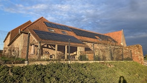 A rustic building with a brick exterior, large windows, and solar panels on the roof. - B&B Hof ter Haegen (Galmaarden)