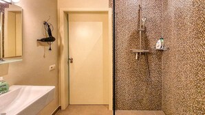 A bathroom with a white sink, a mirror, a shower with a textured wall, and a door. - B&B Hof ter Haegen (Galmaarden)