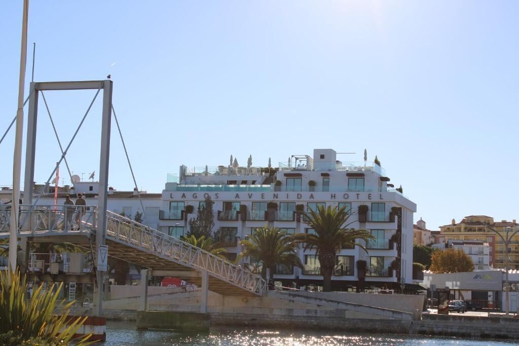 A hotel with a modern design, featuring a prominent entrance with a bridge and a view of the water.