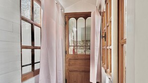 A narrow hallway with wooden doors and windows, leading to a room with a tiled backsplash. - Au Croco fleuri, 50m des arènes, terrasse (Nîmes)