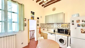 A compact kitchen with a dining area, a washing machine, and a refrigerator. - Au Croco fleuri, 50m des arènes, terrasse (Nîmes)