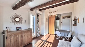 Un intérieur rustique avec des poutres apparentes, un comptoir d’accueil en bois, un coin repas avec une table et des chaises, et un canapé.