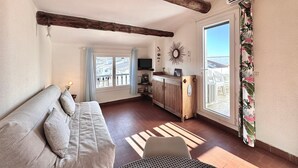 Un salon confortable avec un canapé, un coin repas avec une table et une grande fenêtre donnant sur un beau paysage.