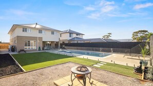 A modern two-story house with a backyard featuring a swimming pool, a patio with a fire pit, and a fenced garden area. - Cowes Market Oasis with private pool (Cowes)