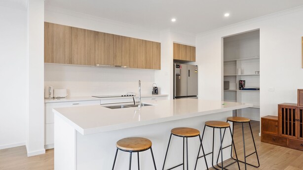 A modern kitchen with a large island, wooden cabinets, and a stainless steel refrigerator. - Cowes Market Oasis with private pool (Cowes)