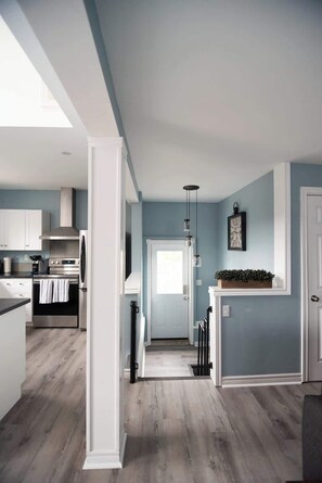 Une cuisine moderne avec des meubles blancs, des appareils en acier inoxydable et un plancher en bois.