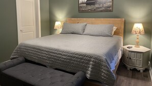 A bedroom with a bed, two bedside lamps, a bench, a door, and a framed picture on the wall. - Unwind and relax at this luxurious mountain retreat. Beautiful Views! (Sparta)