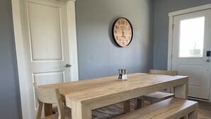 A dining area with a wooden table and benches, a wall clock, and a door. - Unwind and relax at this luxurious mountain retreat. Beautiful Views! (Sparta)