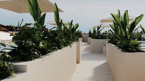 Een dakbostuin met betonnen plantenbakken en grote parasols.