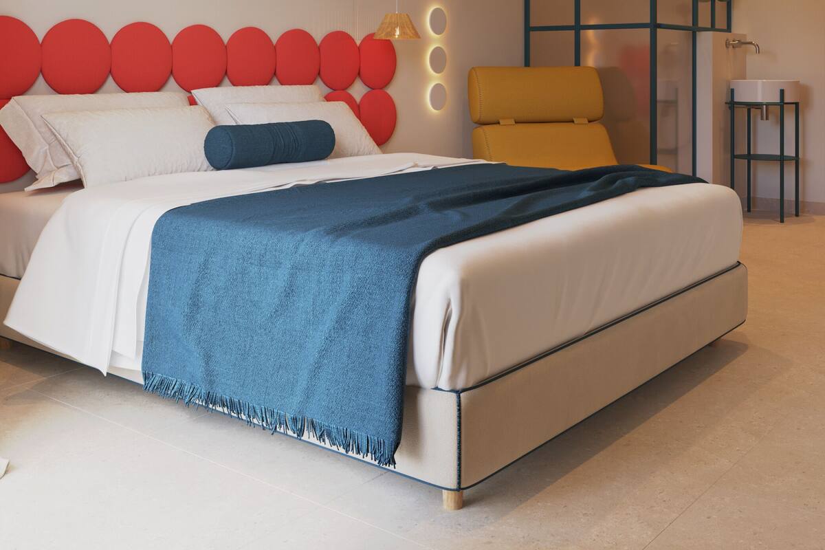 A modern bedroom with a bed, a yellow chair, and a small table with a sink.