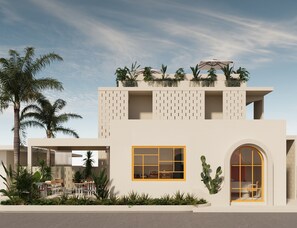 A modern building with a flat roof, a large window with yellow frames, and a cactus on the wall.