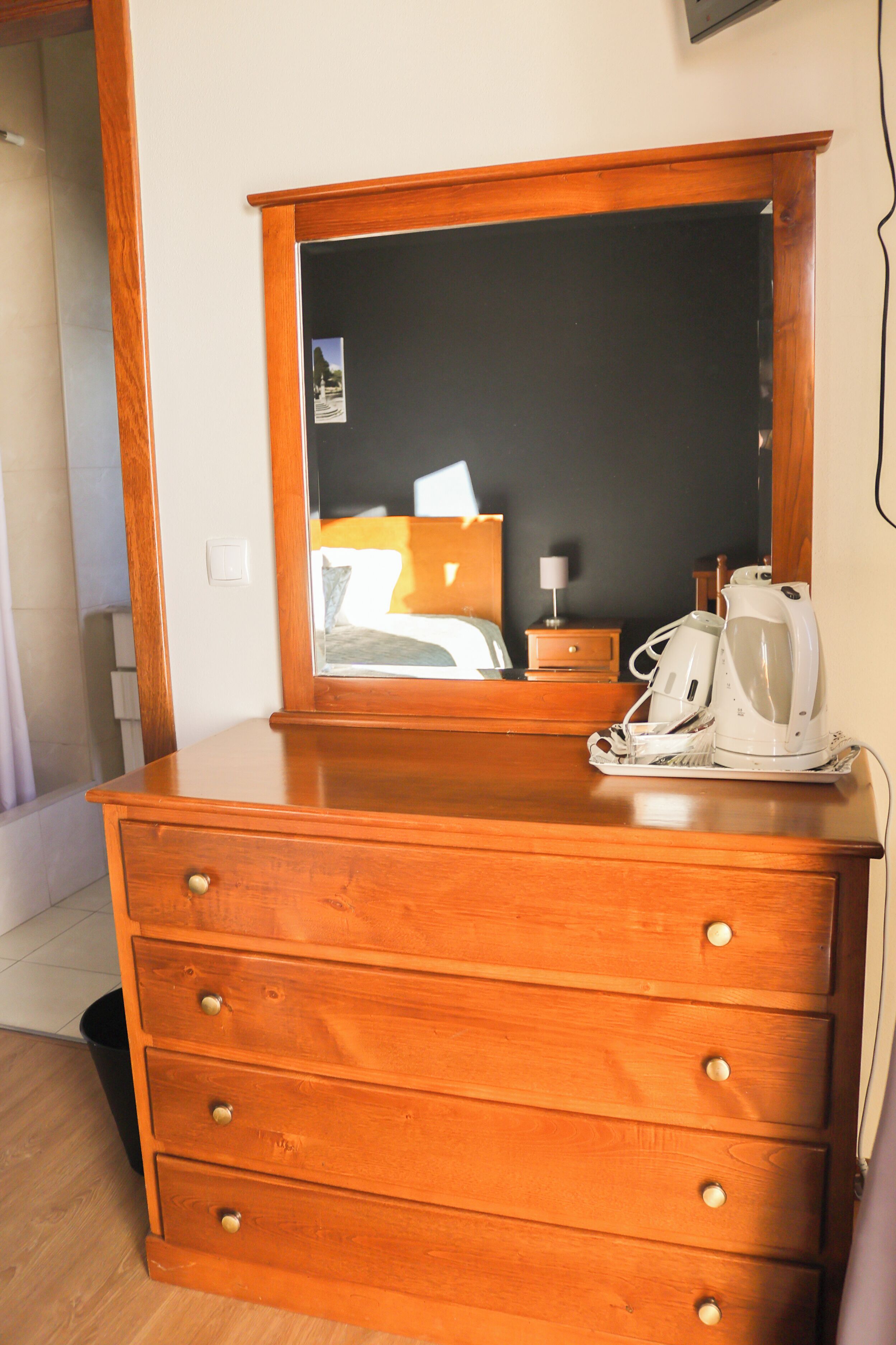 A wooden dresser with drawers and a mirror above it.