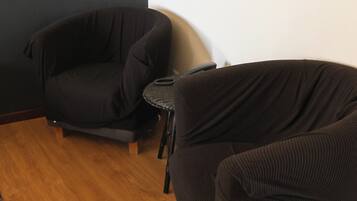 A room with two black sofas, a small table, and a framed picture on the wall.