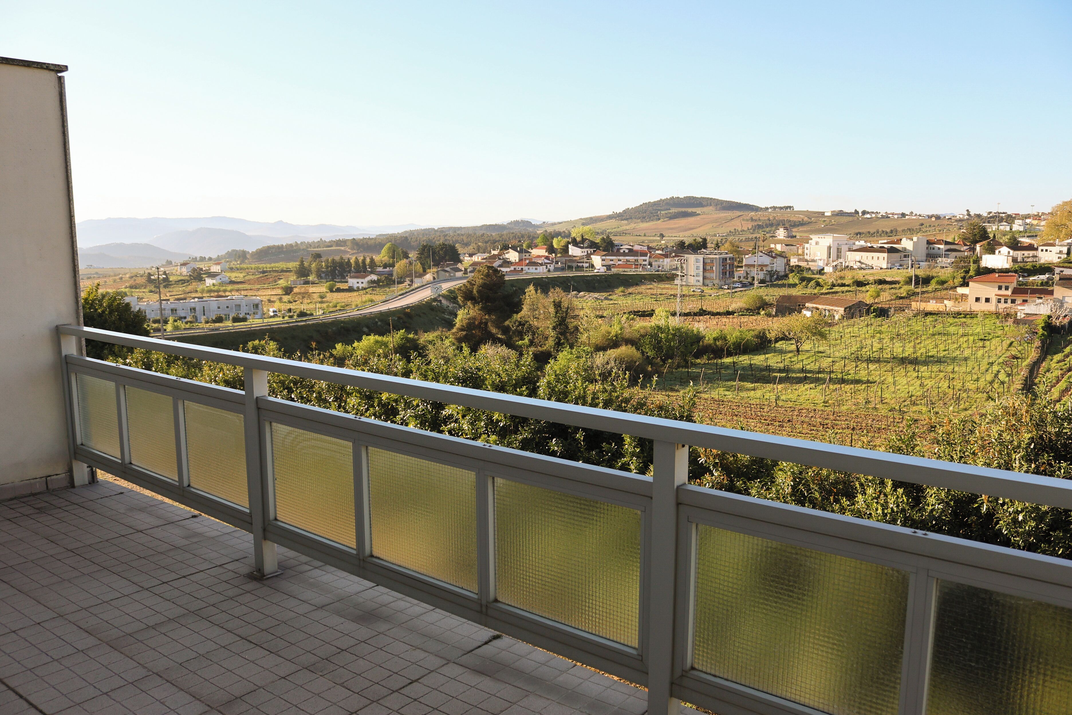 A balcony with a view of a town and vineyards.