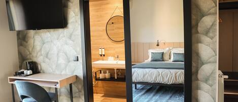 Un dormitorio moderno con una cama, un escritorio y un televisor.