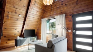 A cozy living room with a sofa, a coffee table, a TV, and a window with curtains.