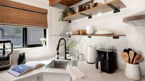 A modern kitchen with a built-in sink, a coffee maker, and wooden utensils on the counter.
