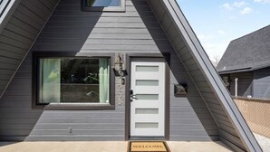 A modern house with a grey exterior, a white front door, and a window with a view.