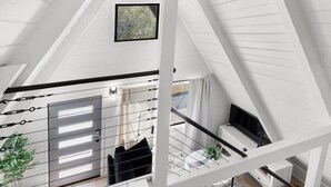 A modern loft-style room with a sloped ceiling, a large window, and a view of the outdoors.
