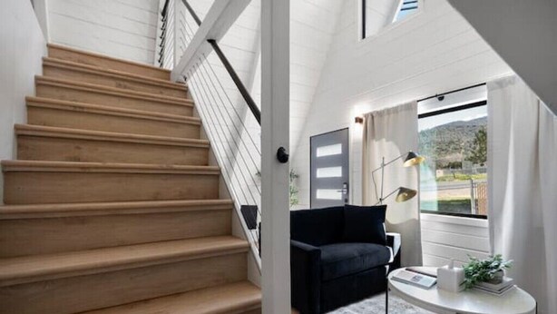 A staircase leading to a room with a black sofa, a small table, and a view of the outdoors.