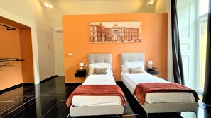 A hotel room with two beds, a large painting on the wall, a black floor, and a door. - Palazzo Goyze (Naples)