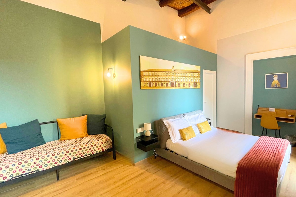 A bedroom with a bed, a smaller bed, a desk, and a chair.