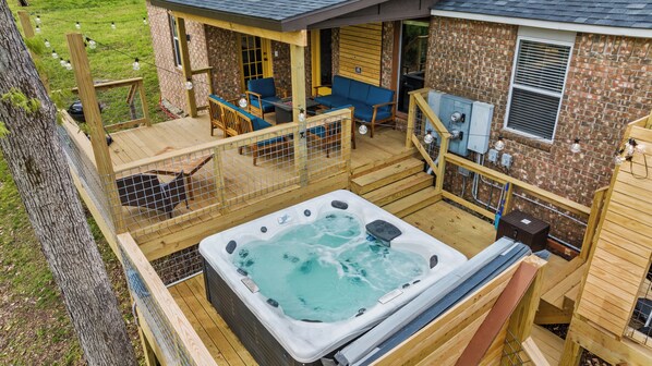 Un jacuzzi en una terraza de madera con un edificio de ladrillo al fondo.