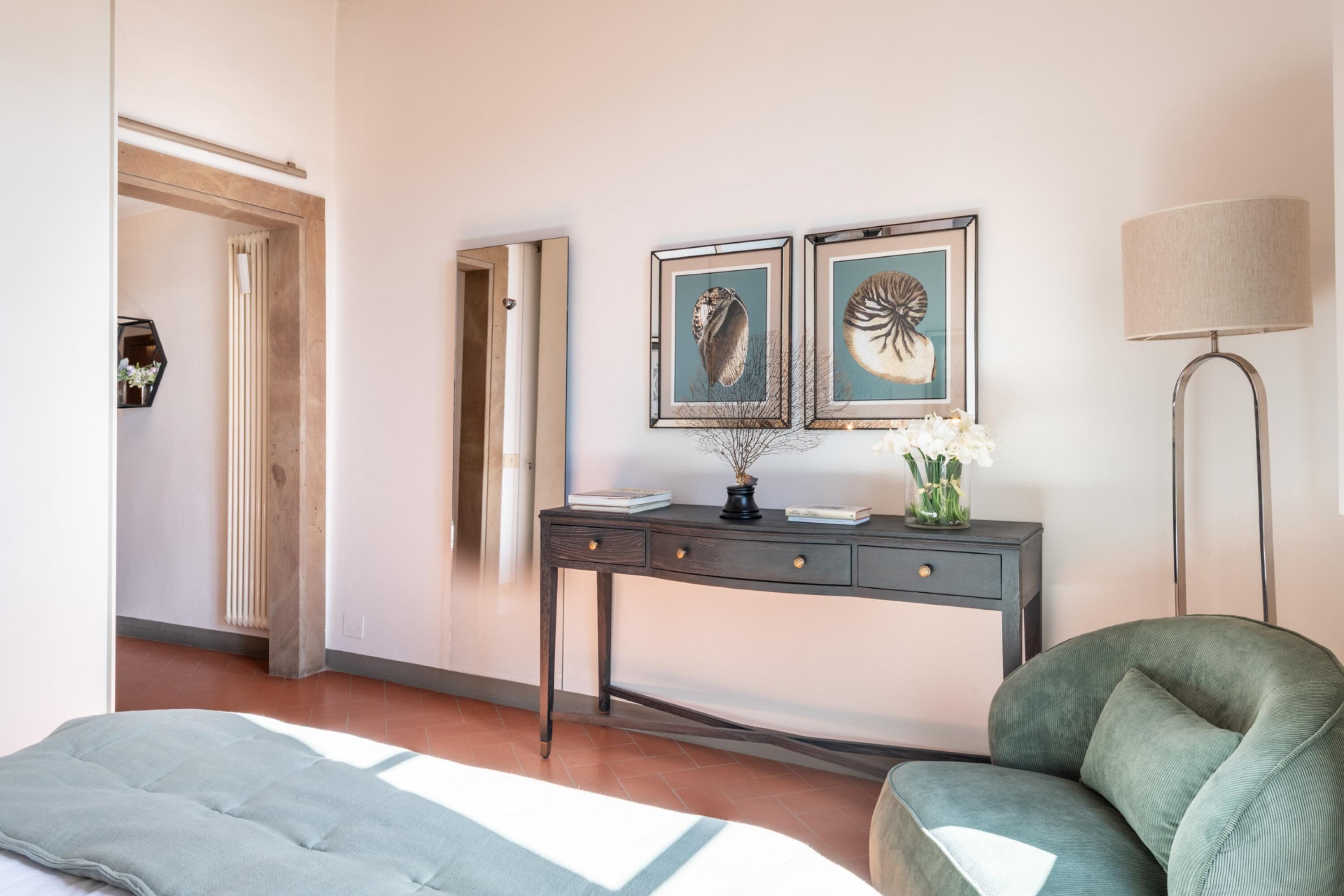 Une chambre d’hôtel avec un lit, un bureau orné de deux tableaux, une lampe et une chaise.