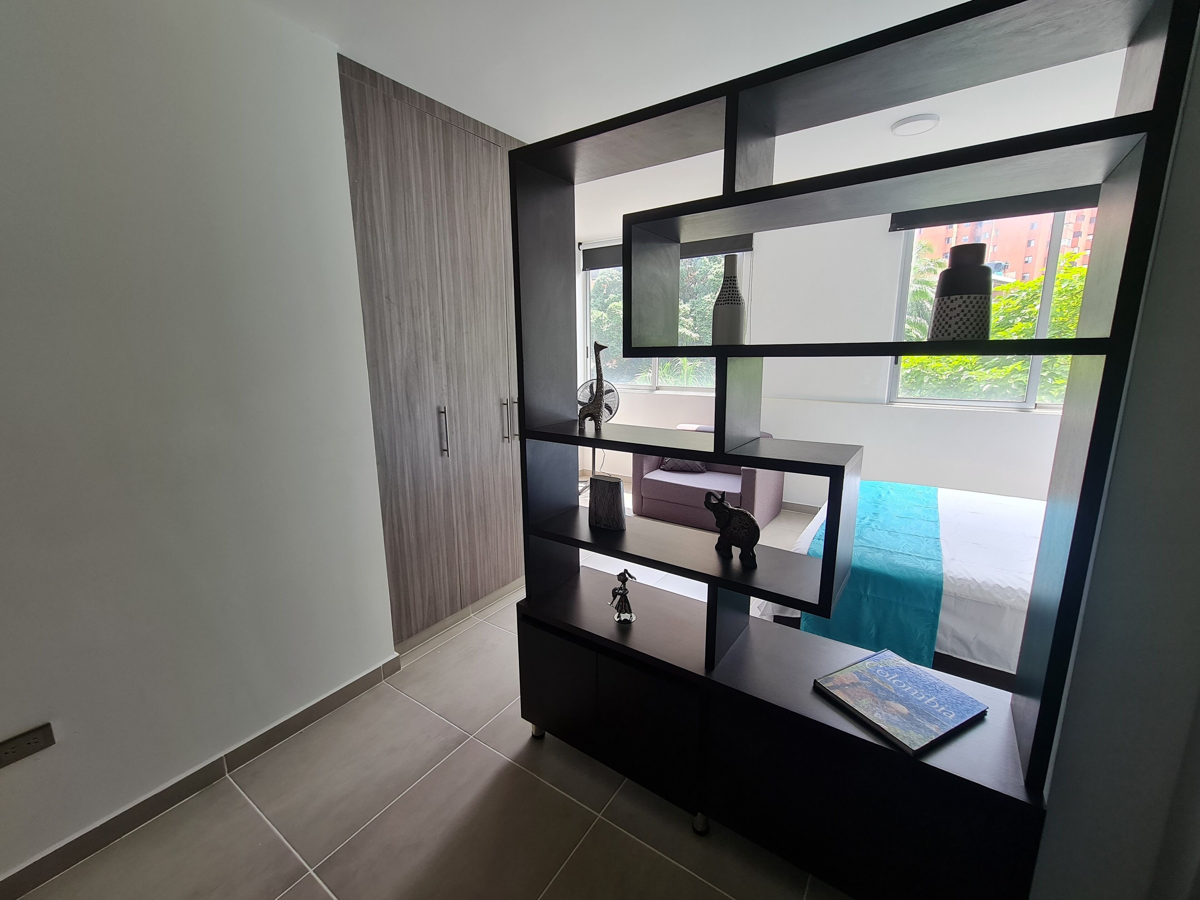 Ein modernes Zimmer mit Kleiderschrank, einem kleinen Tisch und Blick ins Freie.