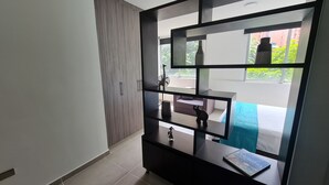 A modern room with a wardrobe, a small table, and a view of the outside. - 403 Moderno Aparta-Suite en Versalles Tipo Loft - Cali Tower Suites & Lofts (Cali)