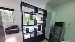 A modern kitchen with a built-in microwave, a refrigerator, and a dining area with a table and chairs. - 403 Moderno Aparta-Suite en Versalles Tipo Loft - Cali Tower Suites & Lofts (Cali)