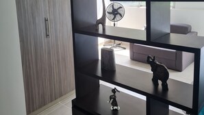 A modern living room with a dark wooden TV stand, a small fan, and a decorative elephant figurine. - 403 Moderno Aparta-Suite en Versalles Tipo Loft - Cali Tower Suites & Lofts (Cali)